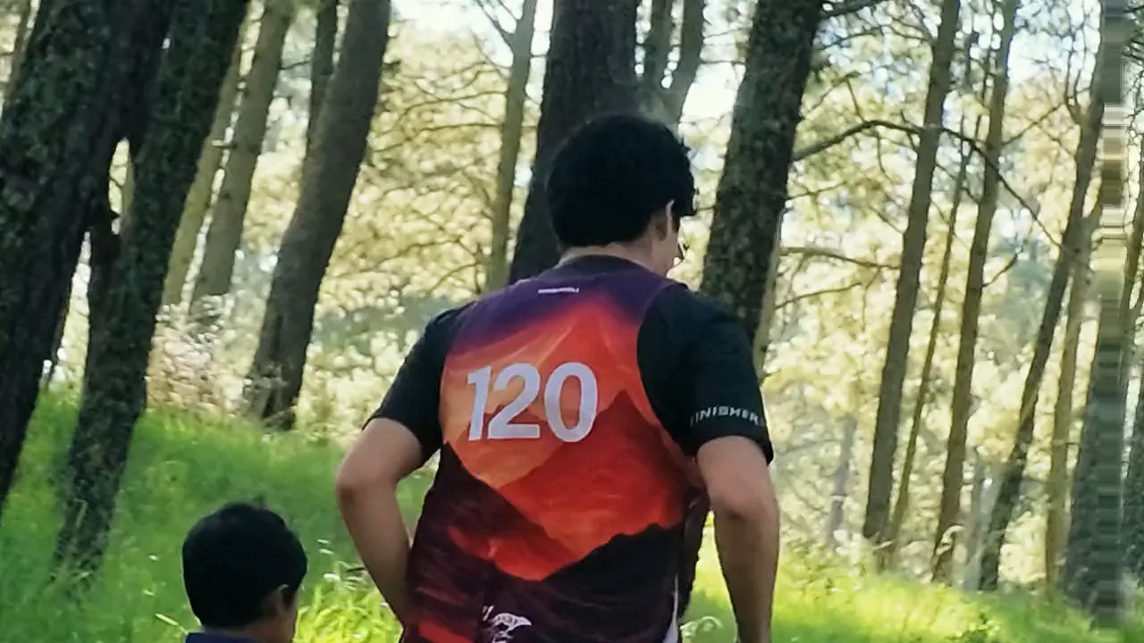 Dos corredores de canicross suben por el pinar tirando del arnés, con su perro