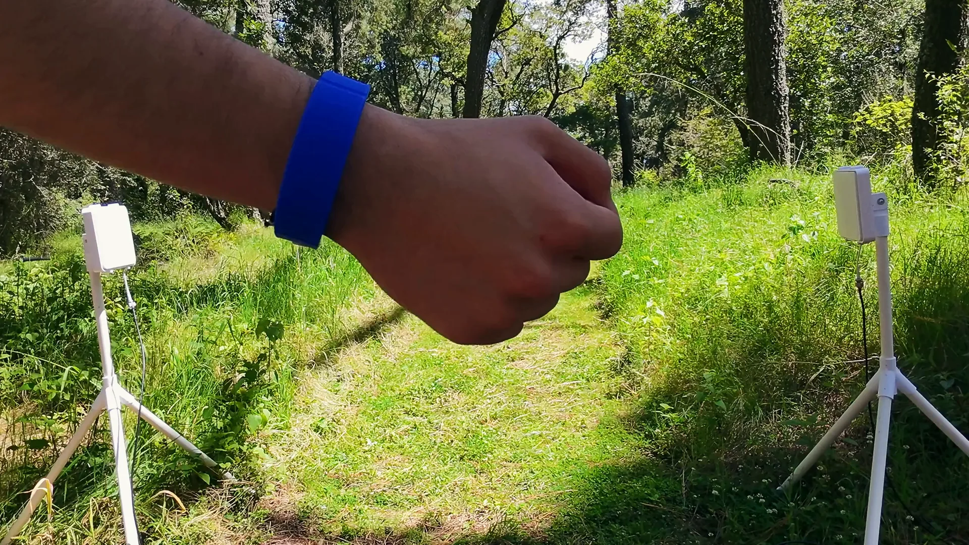 Un corredor cruza entre las dos antenas enfrentadas, montadas sobre trípodes a los lados de un camino de monte